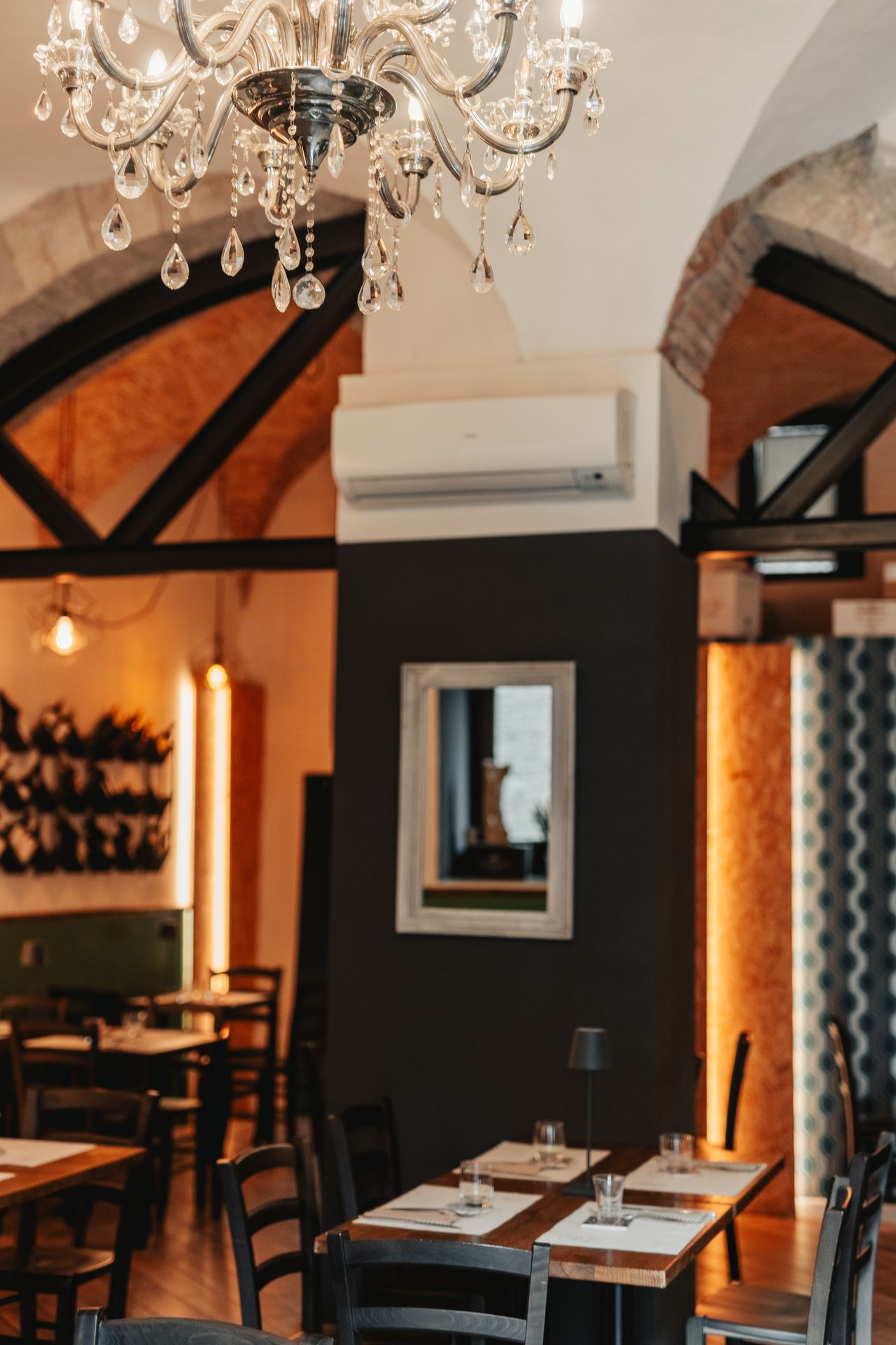 The main dining room of Osteria Cernicchi, with stone arches and the wine wall